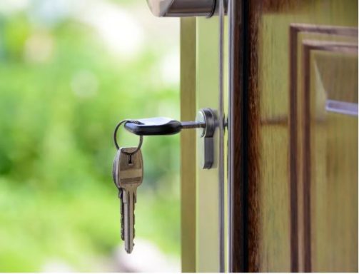 Ein Schlüssel steckt in einem Türschloss, die Tür steht leicht geöffnet.